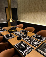 Dining table set with black and white placemats in a modern restaurant setting.