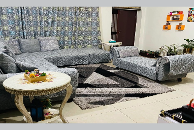 Living room with gray patterned sofa set, round table, and decorative items.