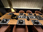 Dining table set with placemats, glasses, and cutlery in a dimly lit room.